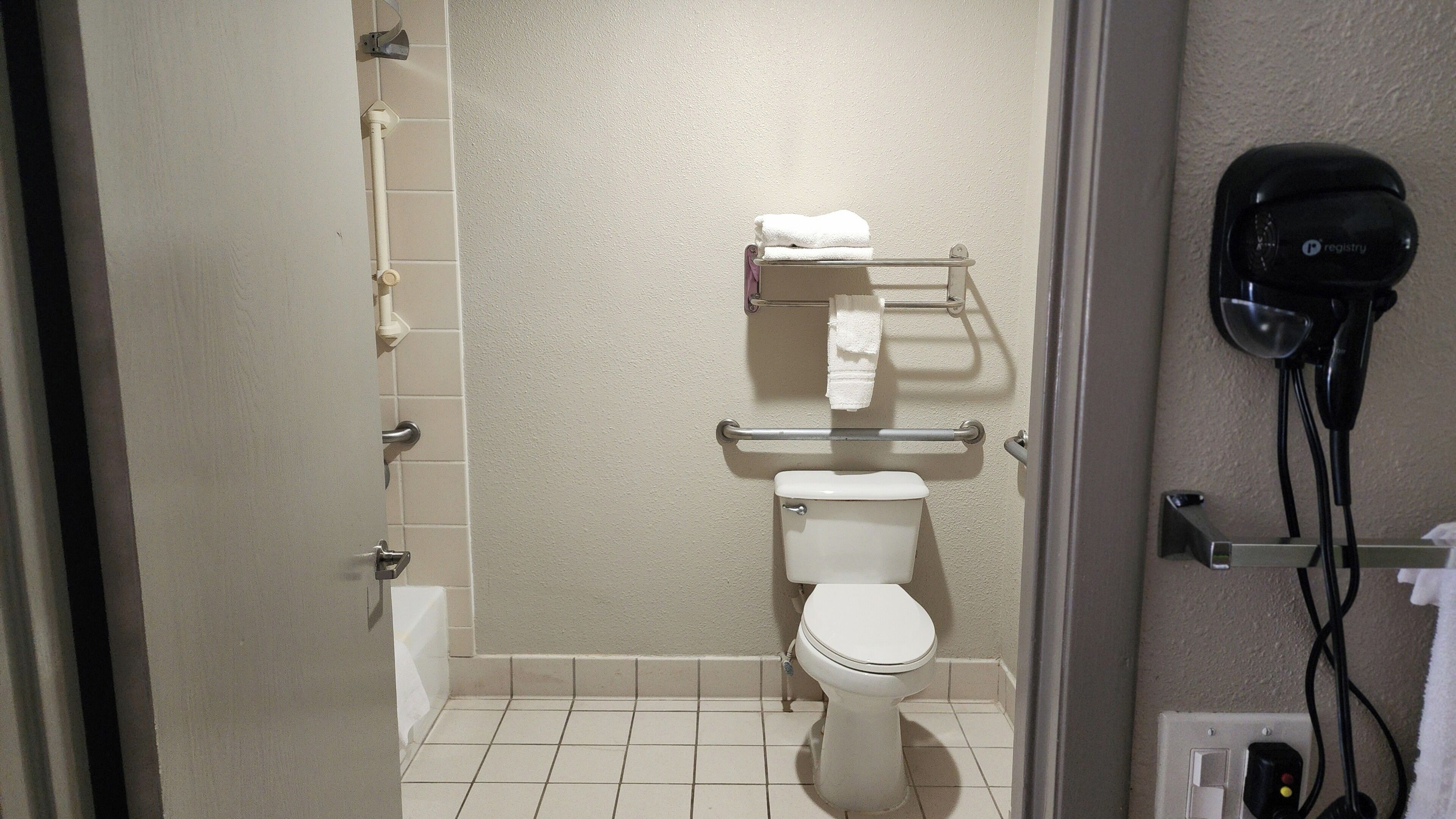 A bathroom with a toilet, a towel rack, and a hand dryer.