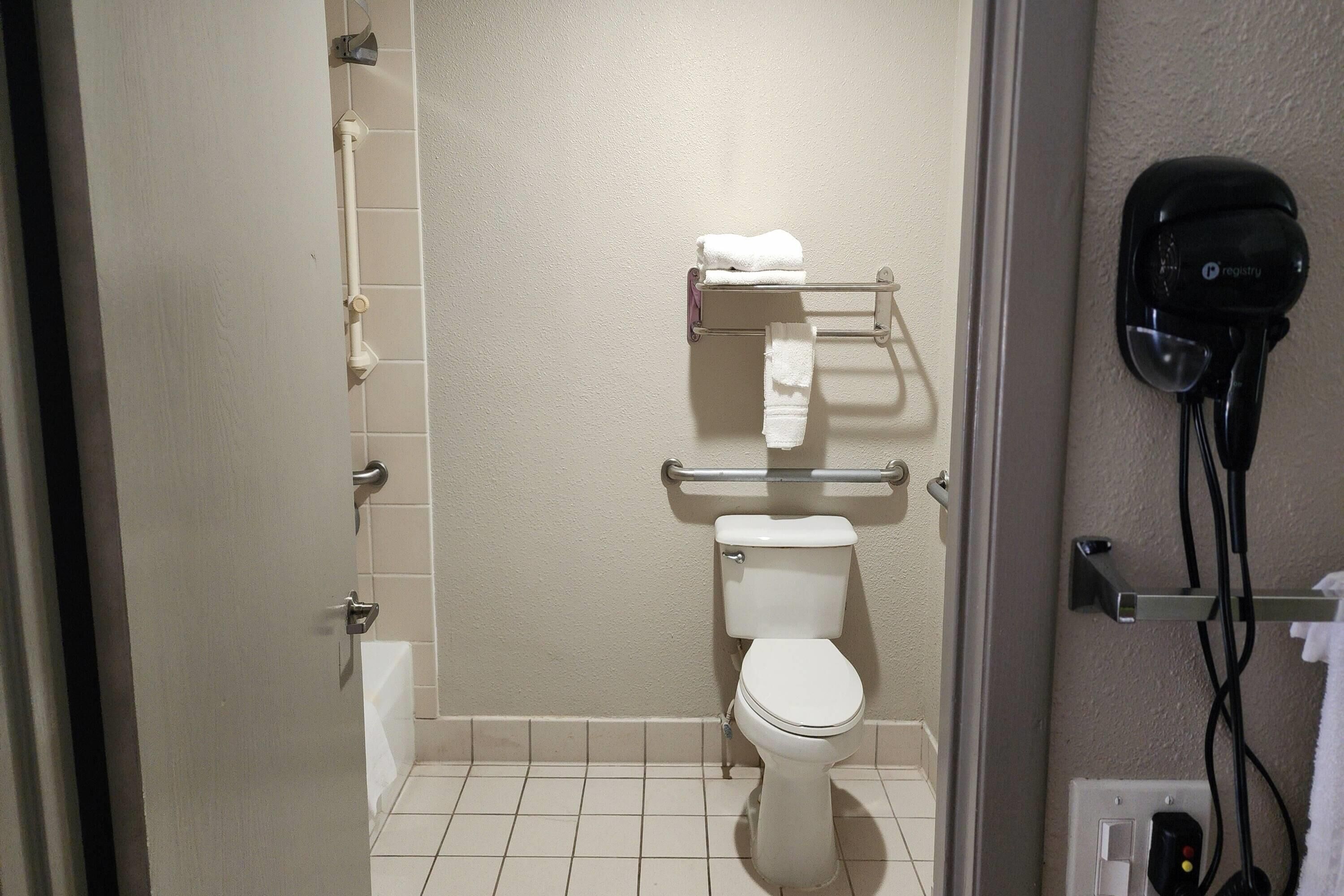A bathroom with a toilet, towel rack, and a hair dryer on the wall.