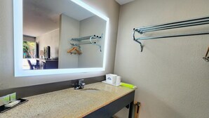 A modern bathroom with a granite countertop, a large mirror, a towel rack, and a sink with a faucet. - Days Inn by Wyndham Seguin TX (Seguin)