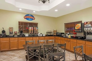 A breakfast area with a counter, seating, and various food and beverage dispensers. - Baymont by Wyndham San Antonio Near South Texas Medical Ctr (San Antonio)