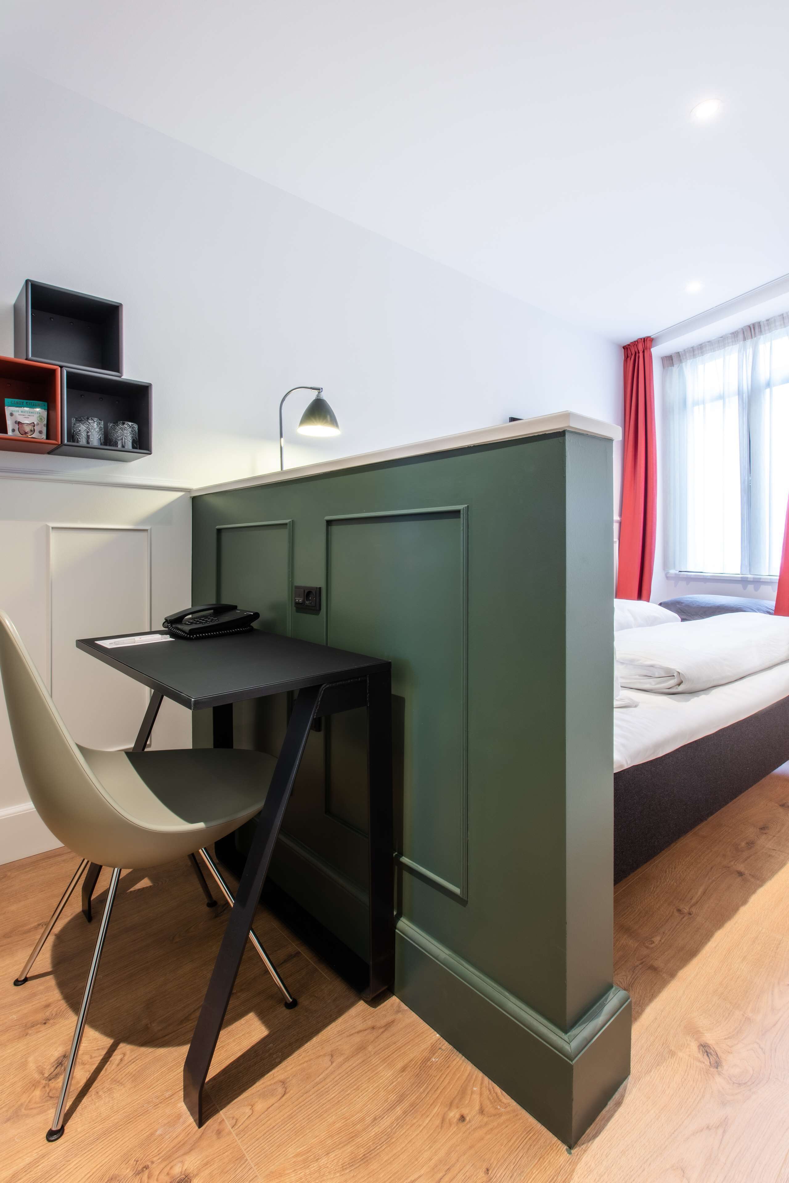 Una habitación pequeña con escritorio, silla y cama.