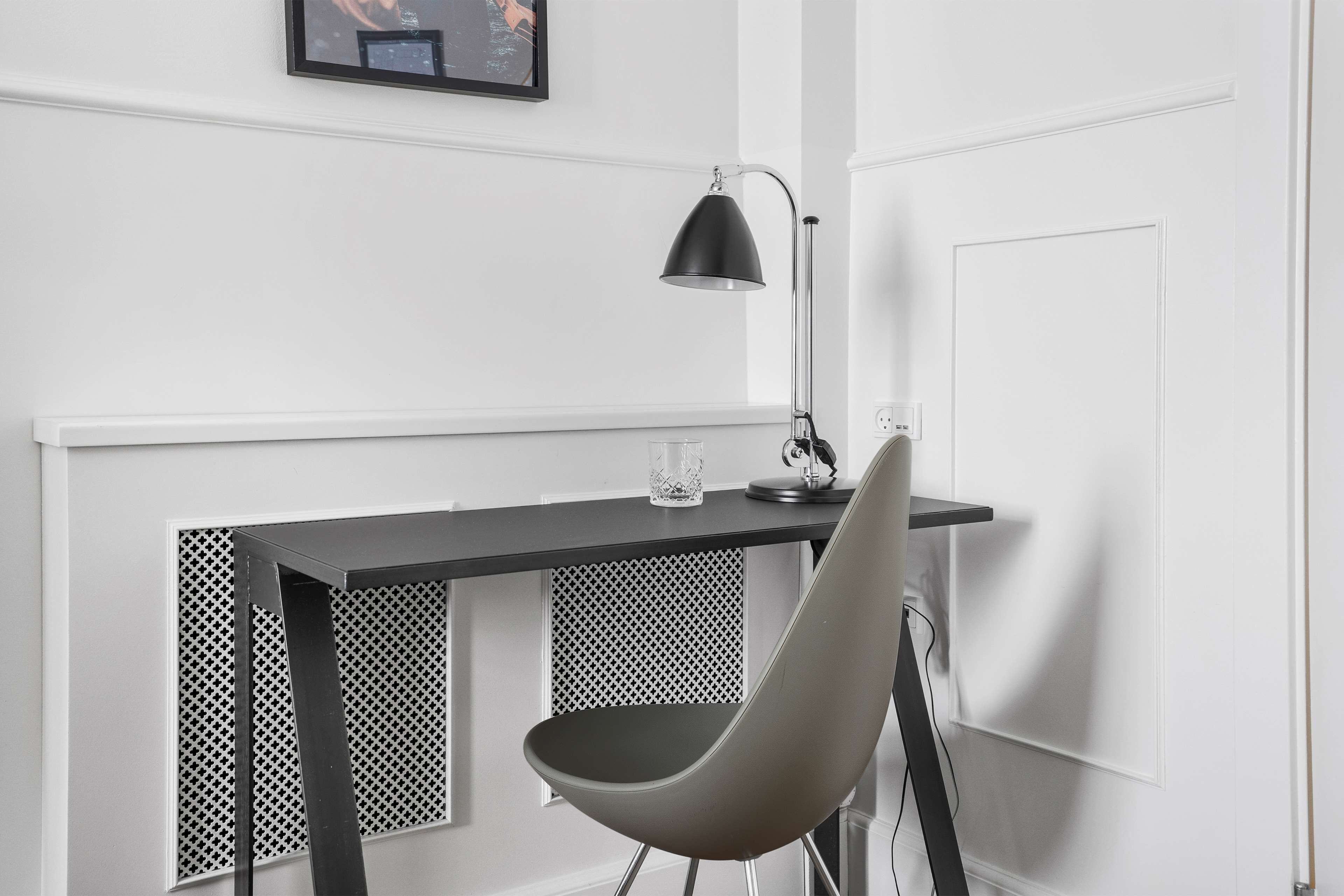 Un escritorio moderno con una lámpara negra, una silla y un objeto decorativo pequeño sobre el escritorio.