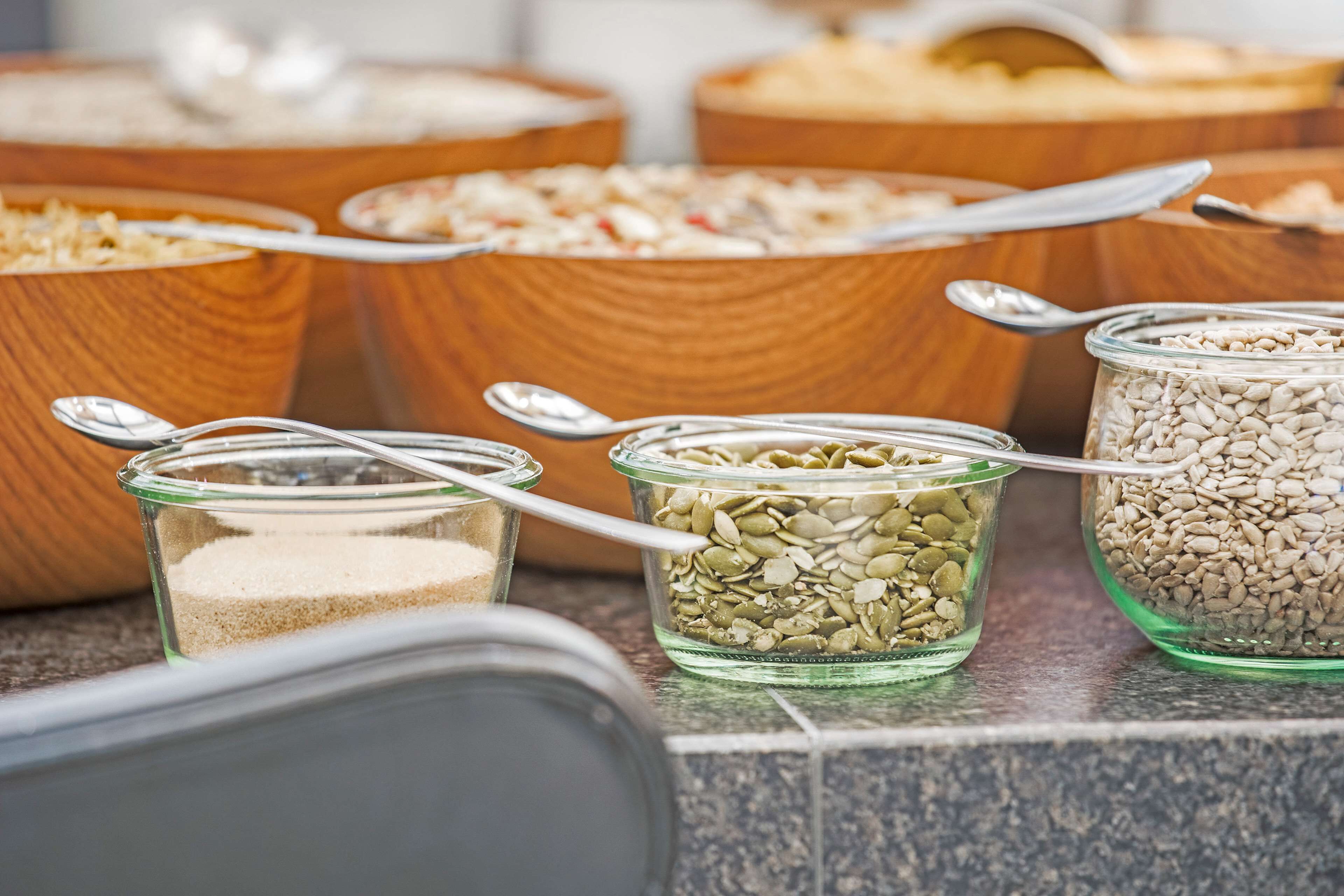 A variety of food items in bowls and jars, including grains and seeds, on a kitchen counter.