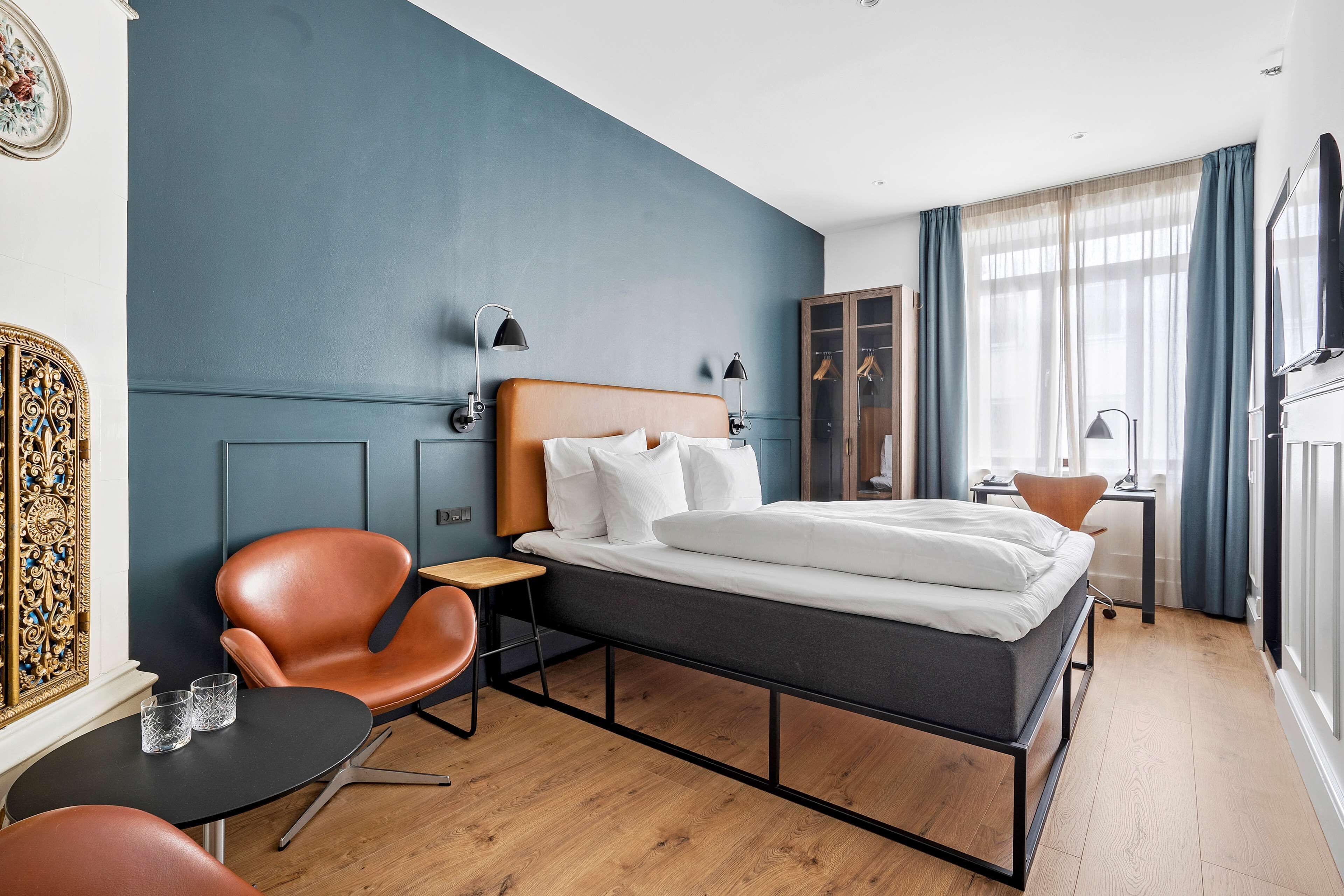Una habitación de hotel moderna con cama, una silla, una mesita y un armario.
