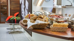 A buffet with various breads, pastries, and a clock on the wall.