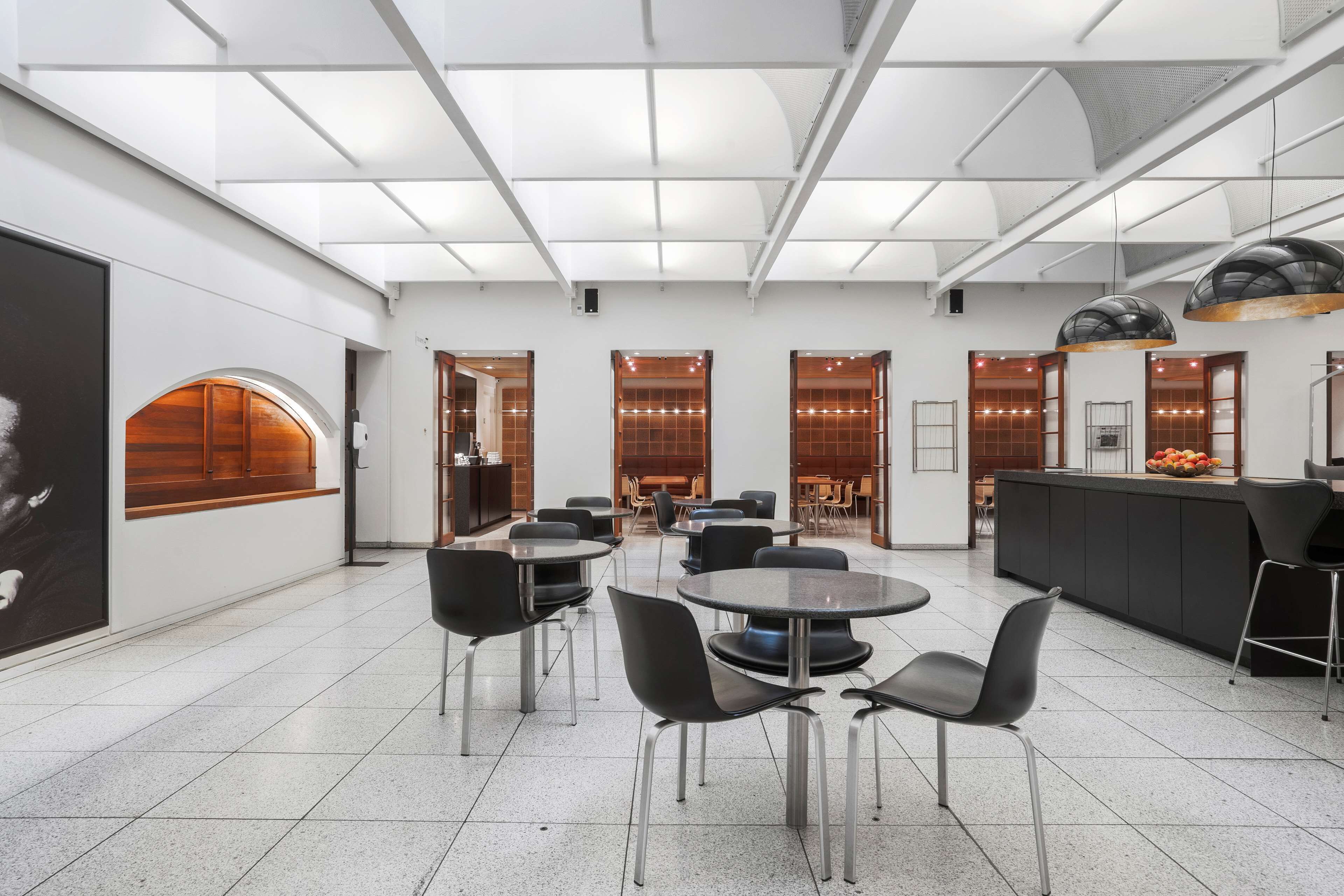 A modern hotel lobby with a central seating area, a bar, and a large poster on the wall.