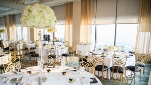 A banquet hall with round tables, gold chairs, and white tablecloths.