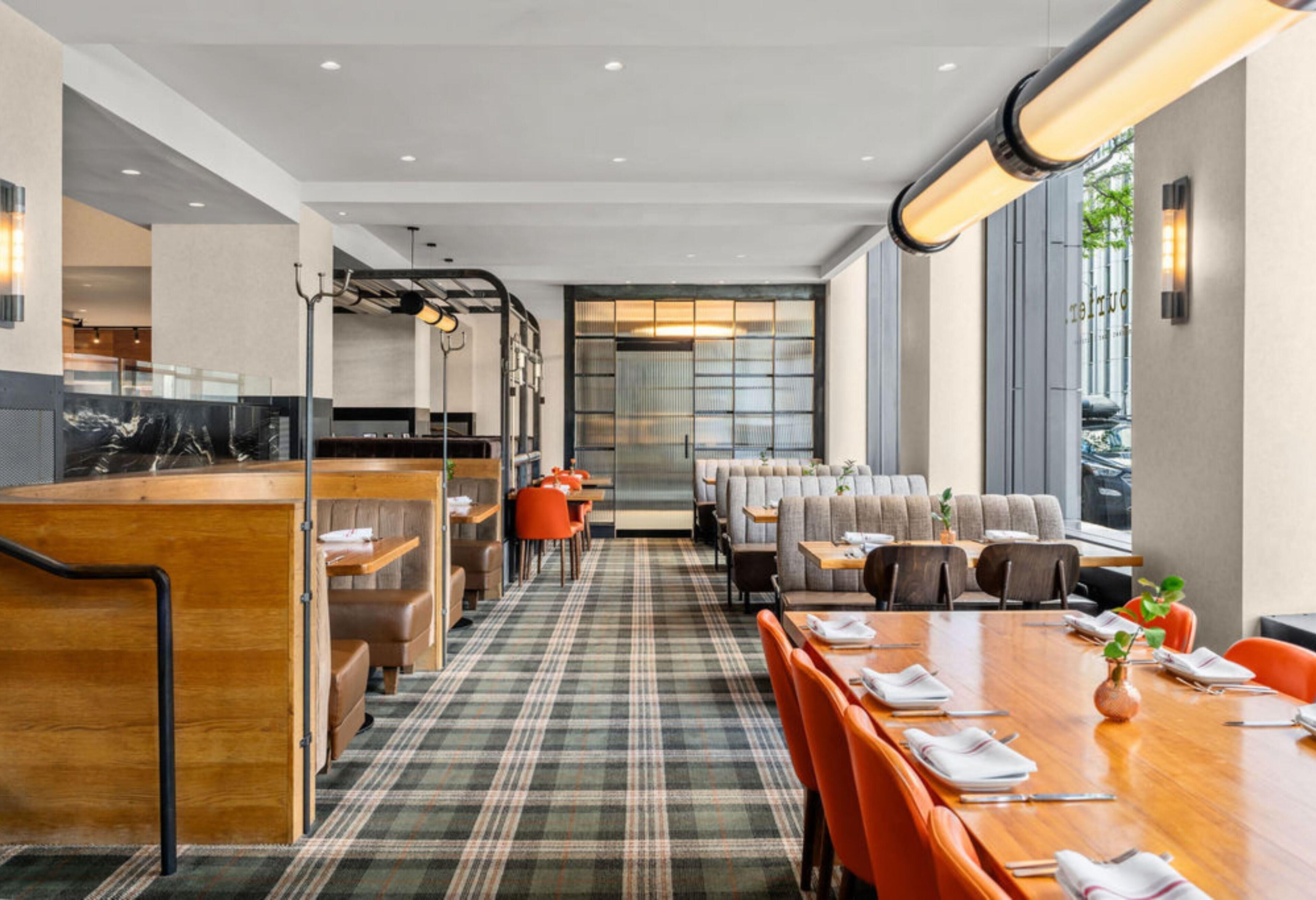 Un hall d’hôtel moderne avec un comptoir d’accueil en bois, un espace salon avec des canapés et des tables, et de grandes fenêtres offrant une vue panoramique.
