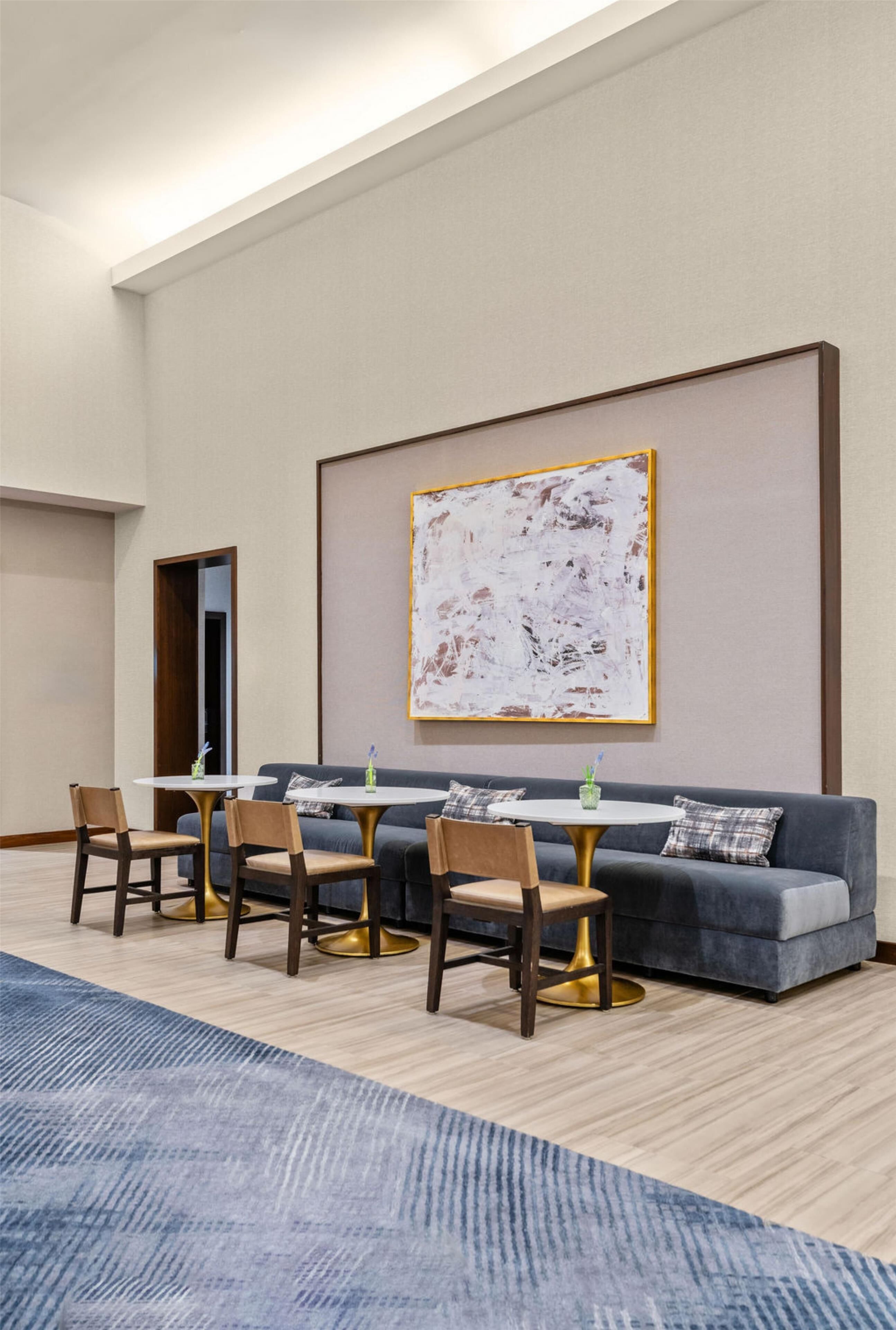 Une chambre d’hôtel moderne avec un canapé, deux tables rondes et des chaises.