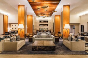 A spacious lobby with a central seating area, high ceilings with wooden paneling, and a fireplace. - Grand Hyatt Denver (Denver)