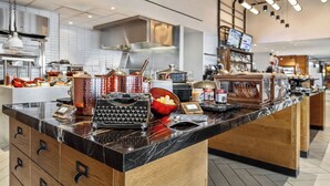 A modern kitchen with marble countertops, stainless steel appliances, and a variety of food items.