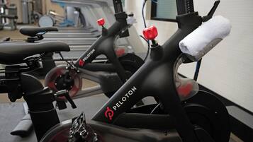 Un vélo d’appartement, avec une serviette sur le siège, une bouteille d’eau et un bouton rouge.