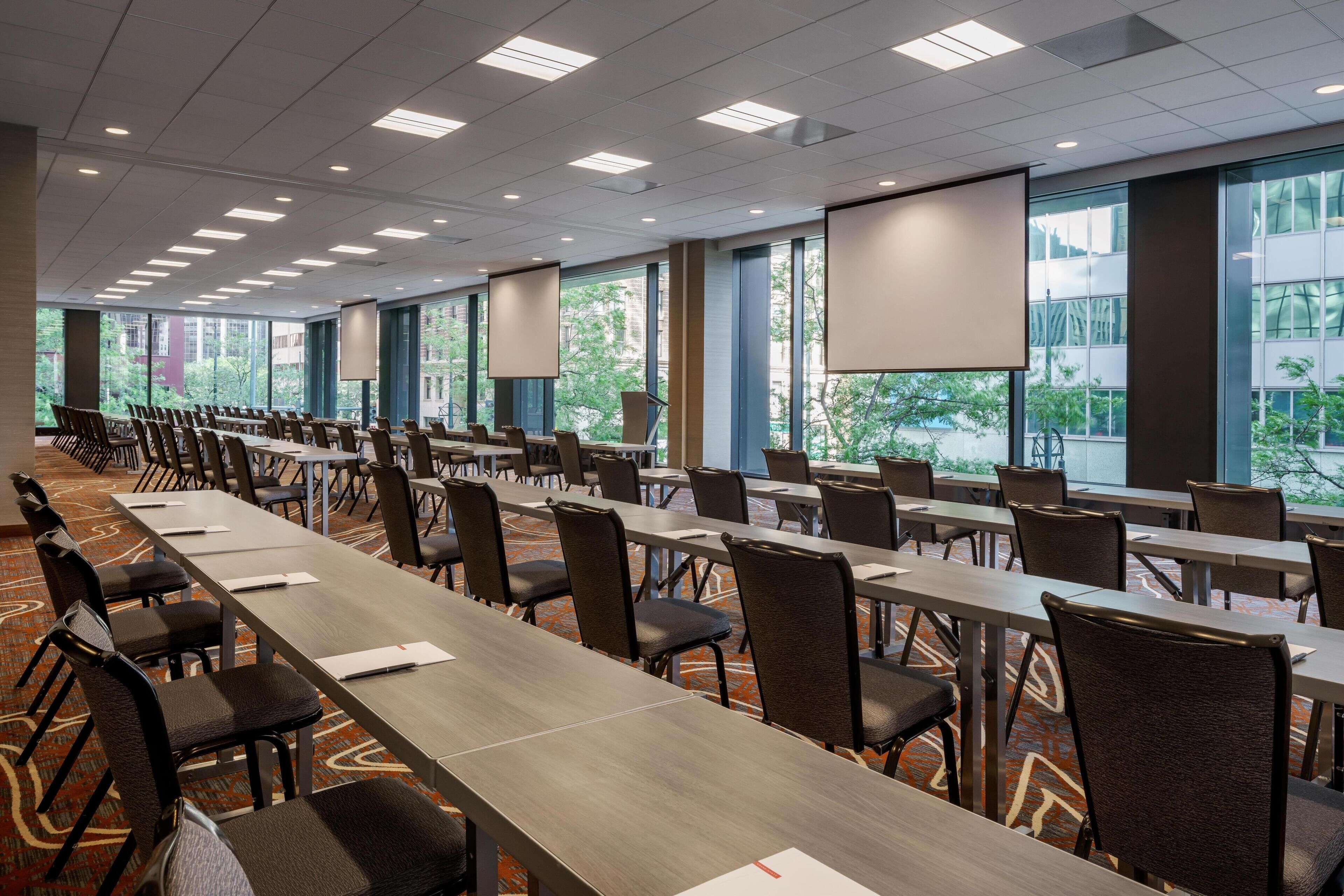A conference room with long tables, chairs, and large windows.
