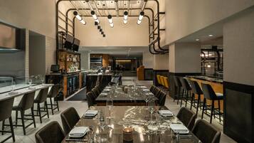 A modern dining area with a long table set for a meal, surrounded by chairs.