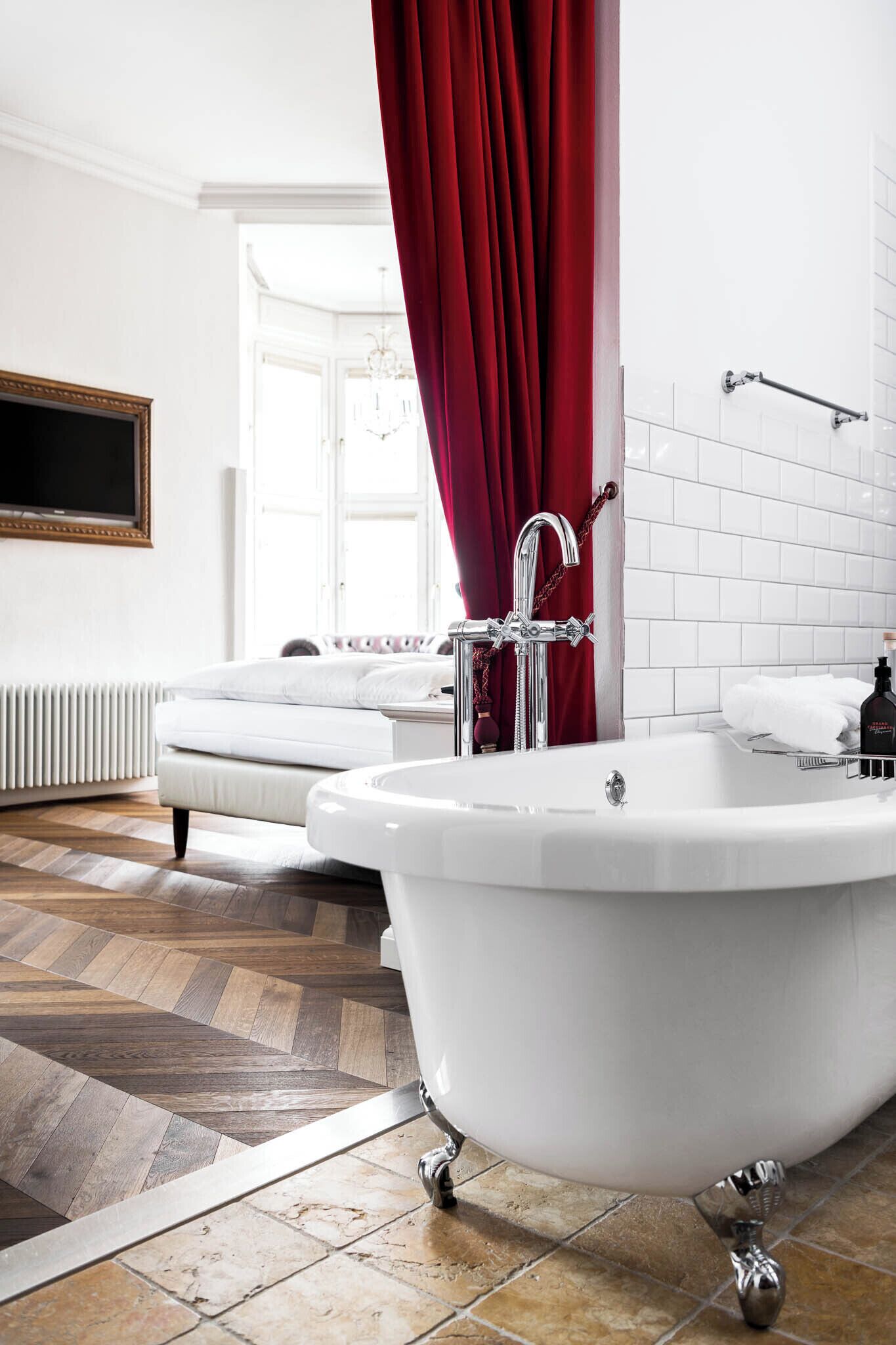 A modern bathroom with a freestanding bathtub, a white radiator, and a patterned floor.