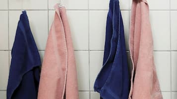 A bathroom with white tiled walls and two towel racks holding pink and blue towels.