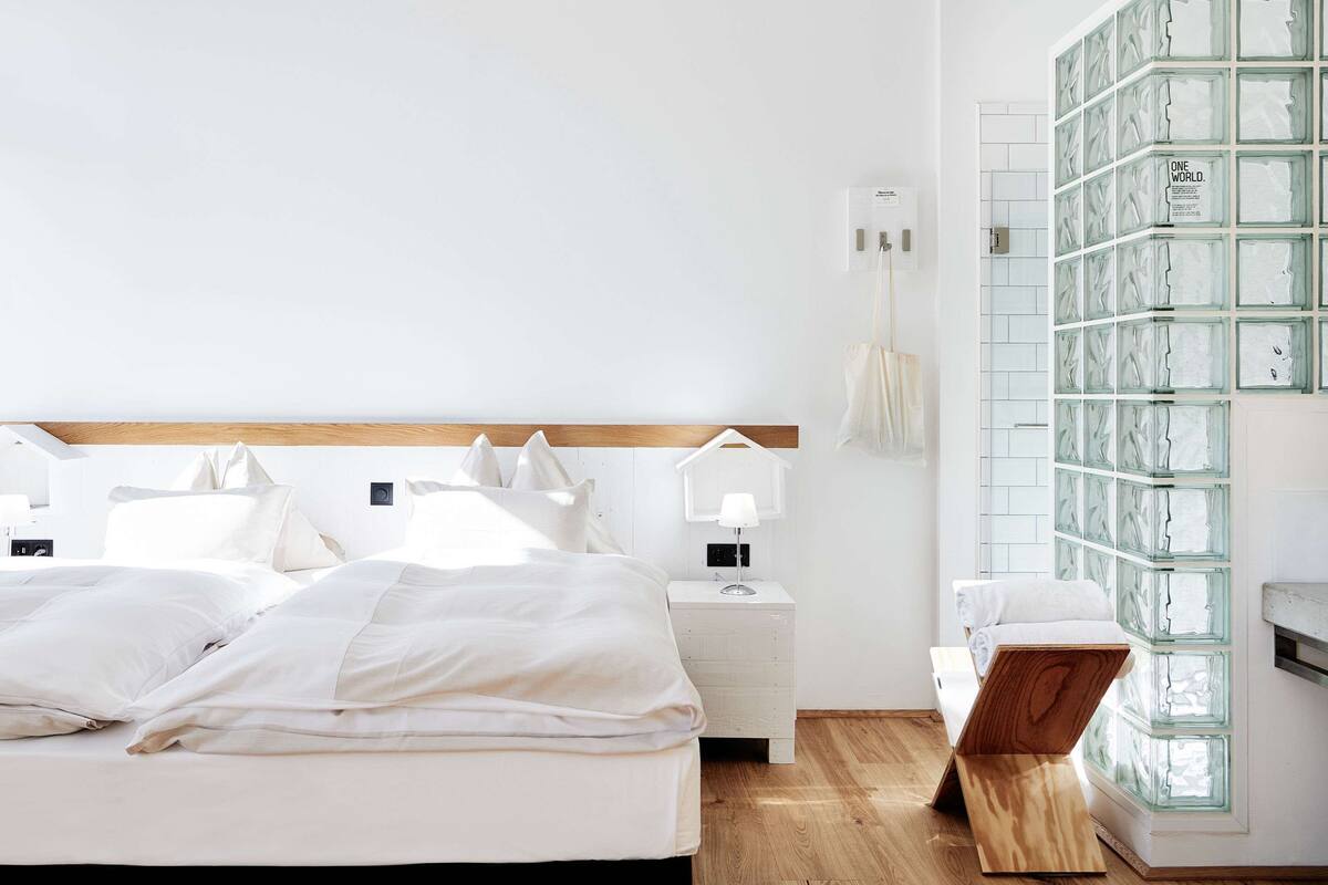 A bedroom with a wooden headboard, a bedside table with a lamp, and a glass display unit.