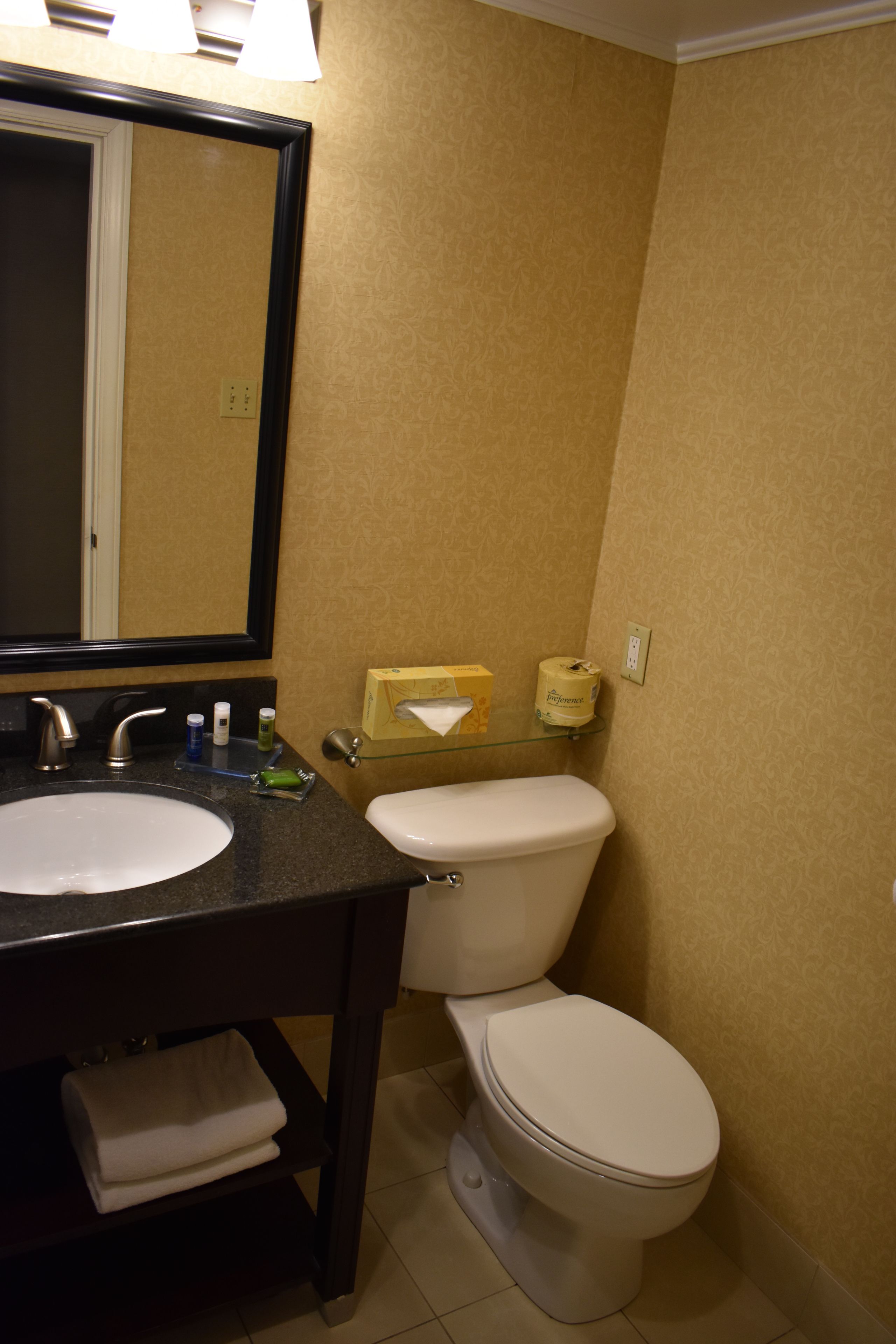 A bathroom with two sinks, a toilet, a mirror, and a tissue box.