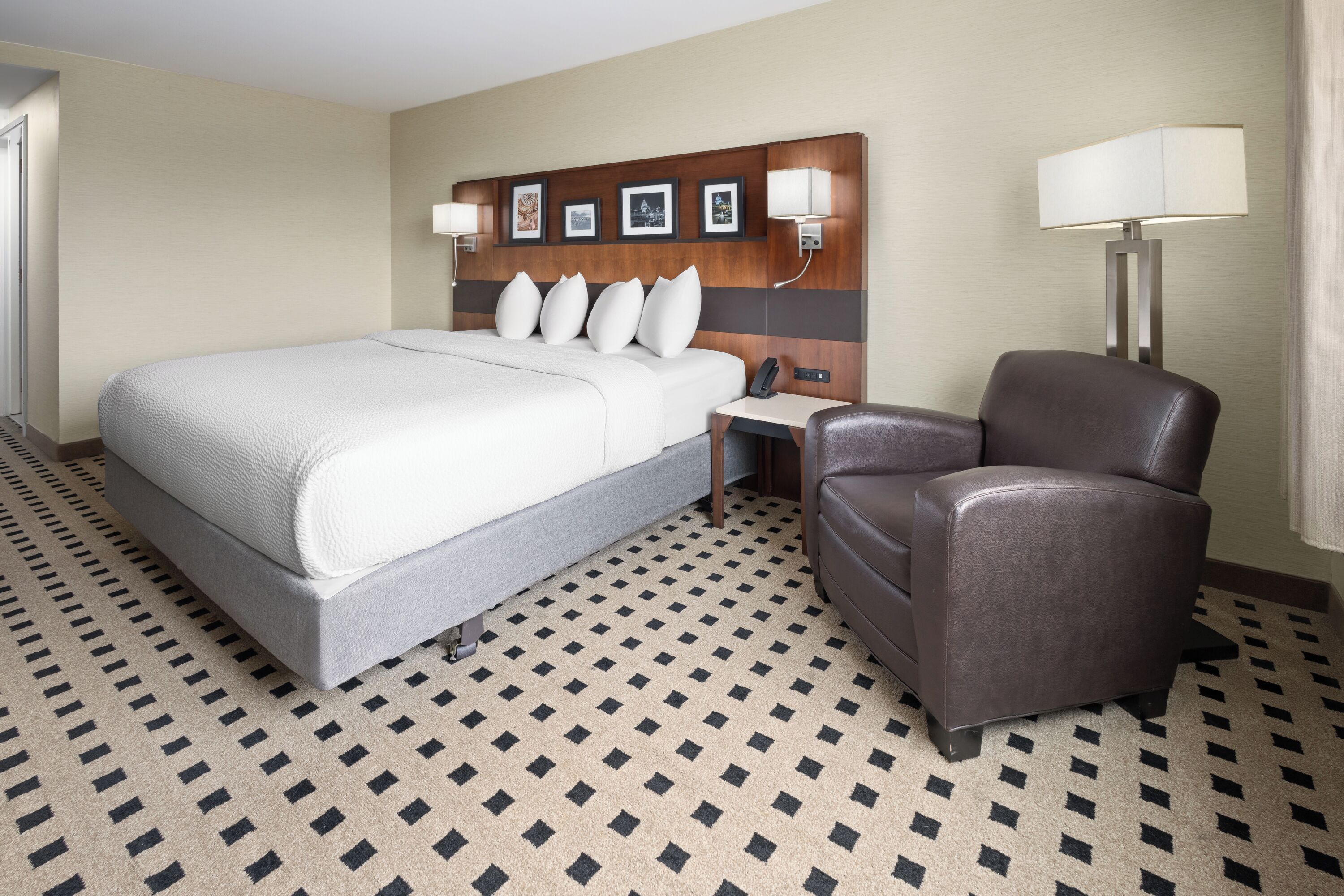 Een hotelkamer met een bed, een bureau, een stoel en een lamp.