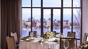 A dining area with a table set for six, overlooking a waterfront cityscape. - Delta Hotels by Marriott Victoria Ocean Pointe Resort (Victoria)