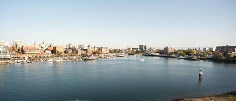 A waterfront cityscape with a marina, buildings, and a lighthouse.