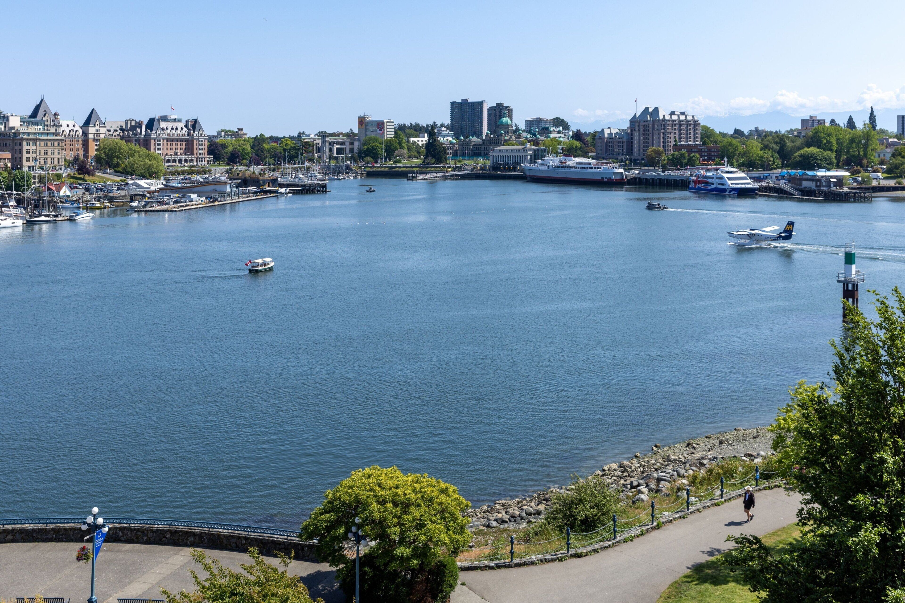 A waterfront cityscape with a marina, boats, and a large cruise ship docked.