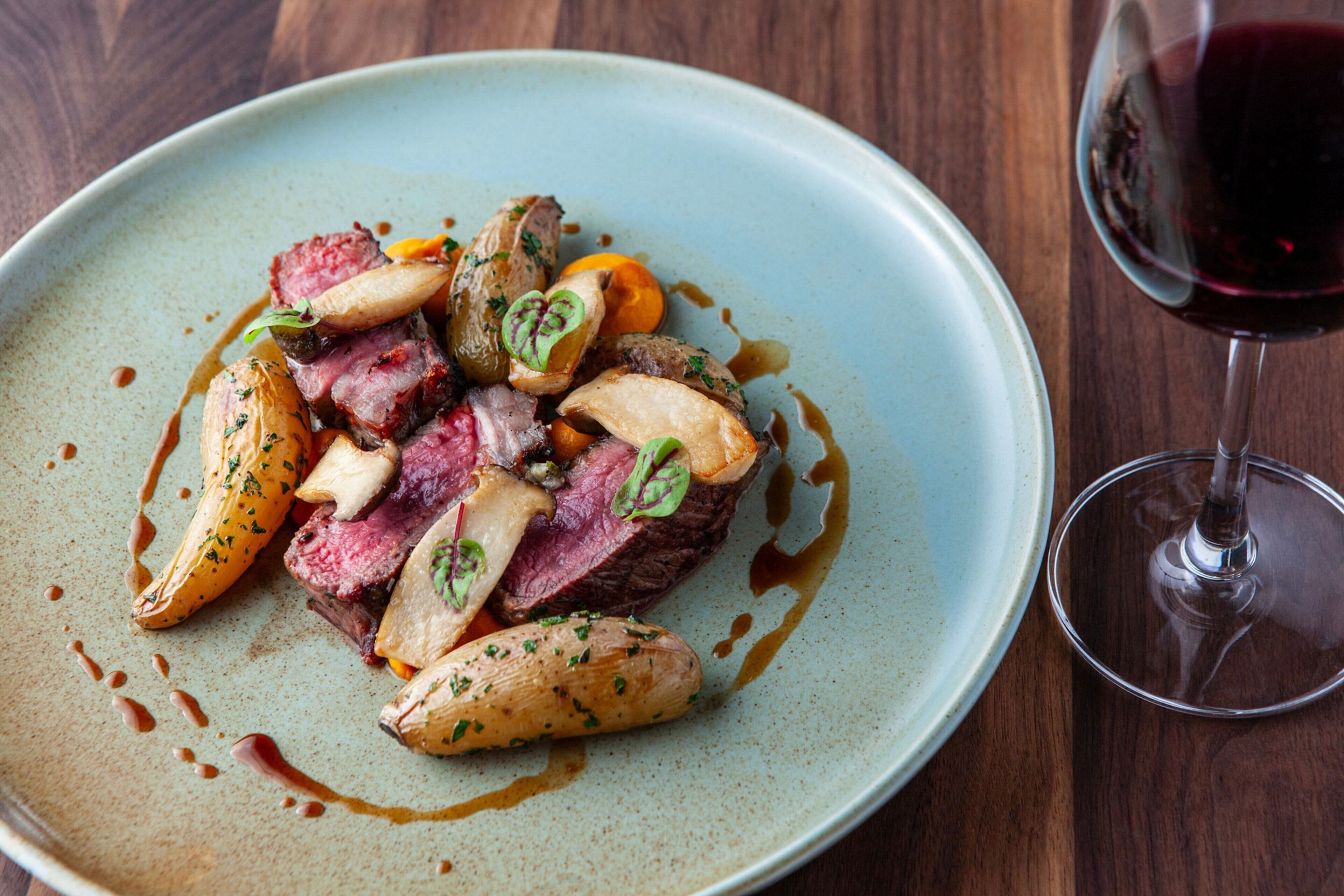 A plate of food with a glass of red wine on a wooden table.