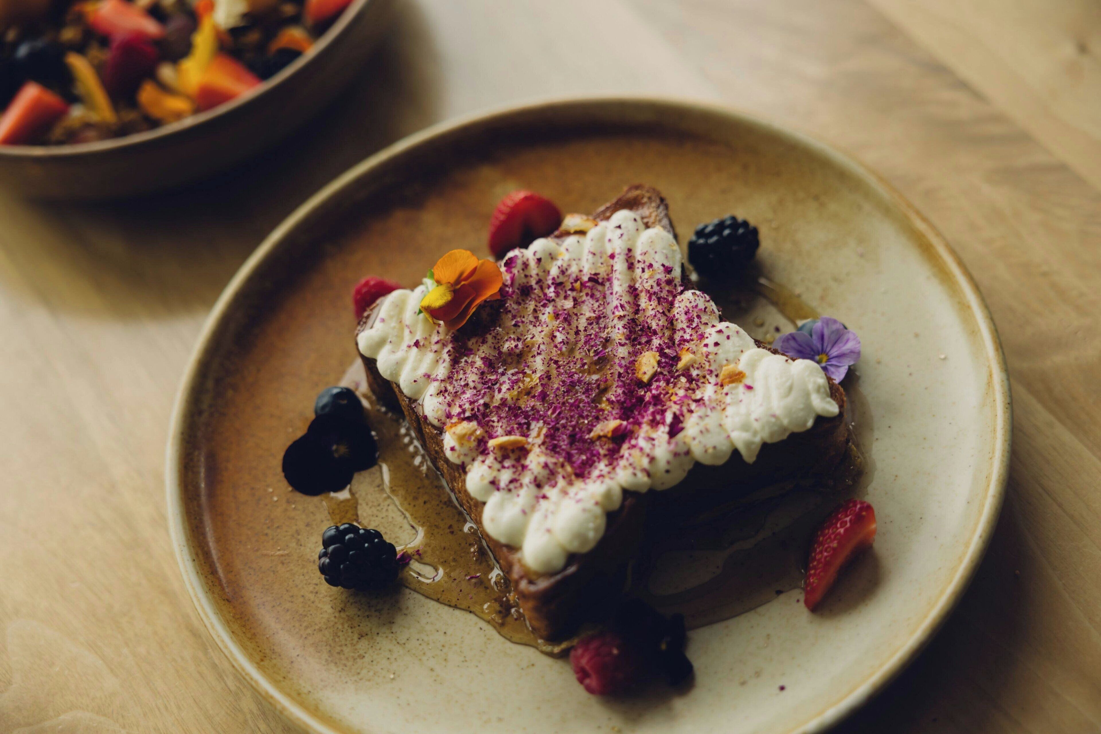 Dessert auf einem Teller mit Beeren und einer Blütenverzierung.