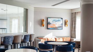 Un hall d’hôtel moderne avec un espace salon, une grande fenêtre et un tableau accroché au mur.