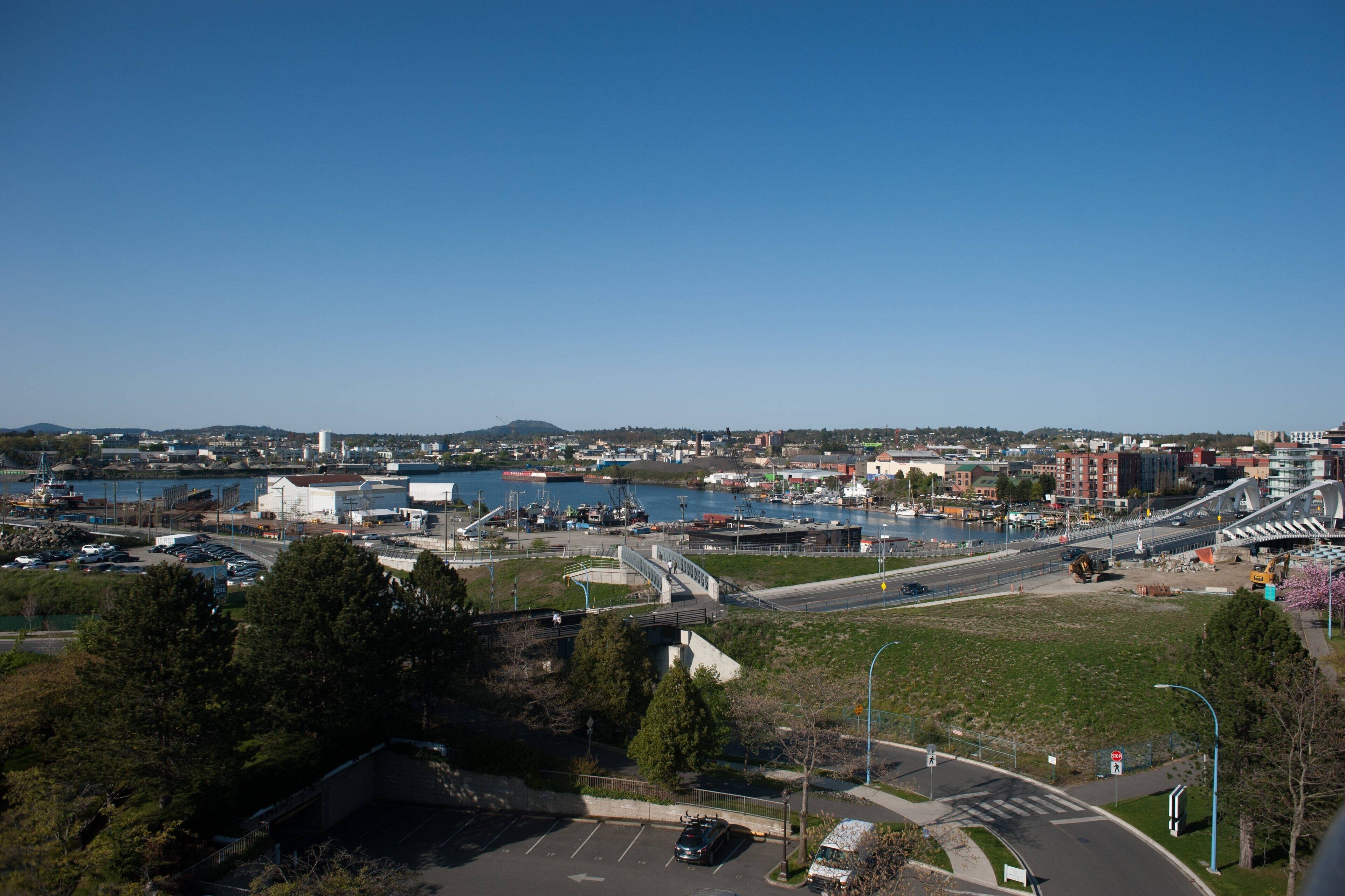 Un paysage urbain côtier avec un port de plaisance, des bâtiments industriels et un pont.