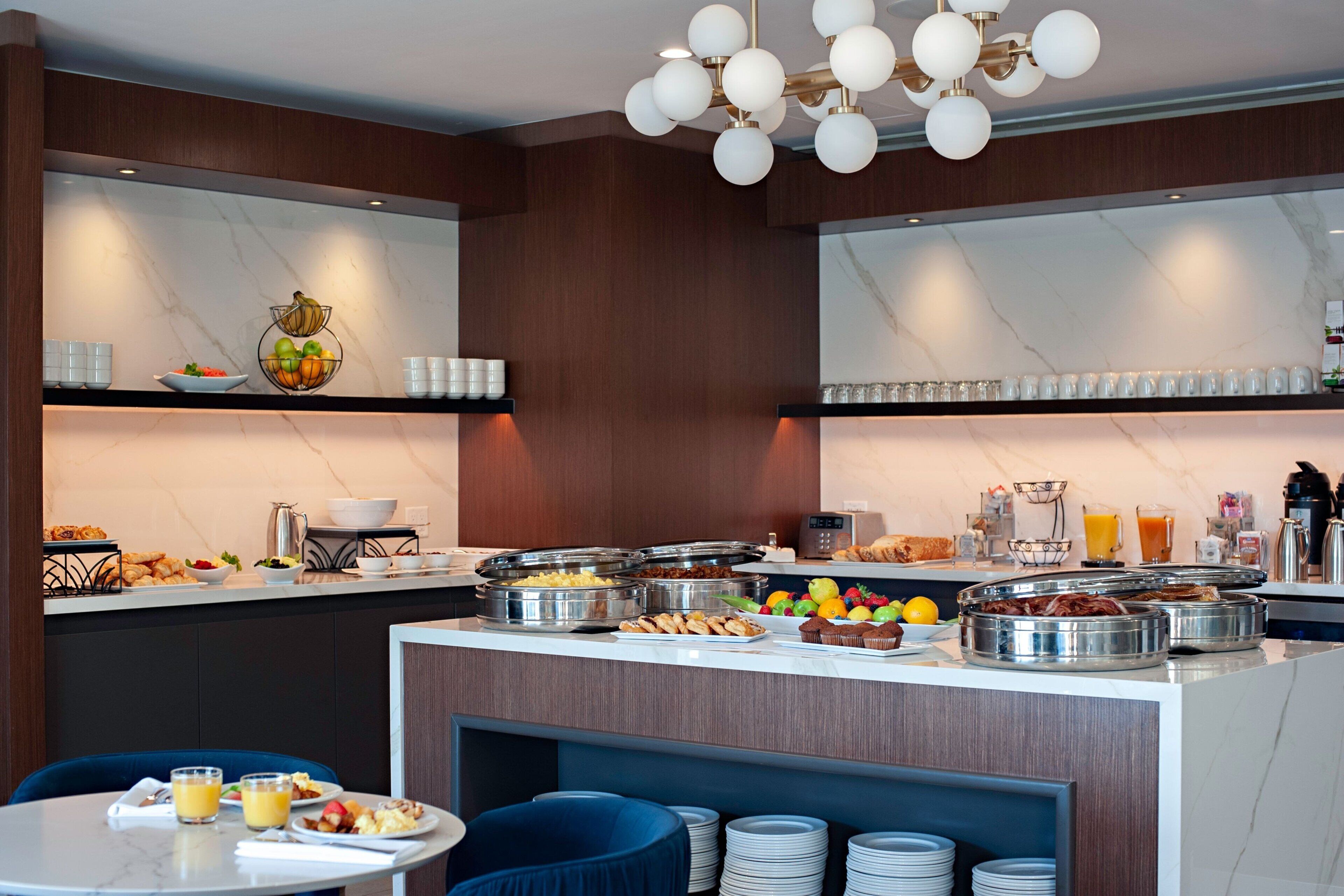 A breakfast buffet with various food items and beverages, a coffee station, and seating arrangements.