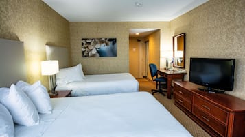 A hotel room with two beds, a desk with a chair, a television, and a painting on the wall.
