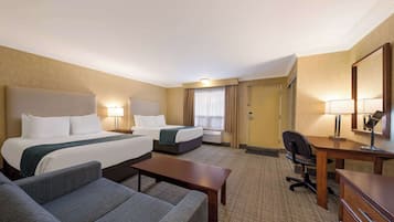 Una habitación de hotel con una cama grande, dos camas individuales, un escritorio, una silla, un sofá y un aparador.