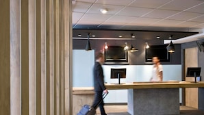 A modern reception desk with pendant lighting, a large screen, and a counter. - ibis Bordeaux Centre Gare Saint Jean (Bordeaux)