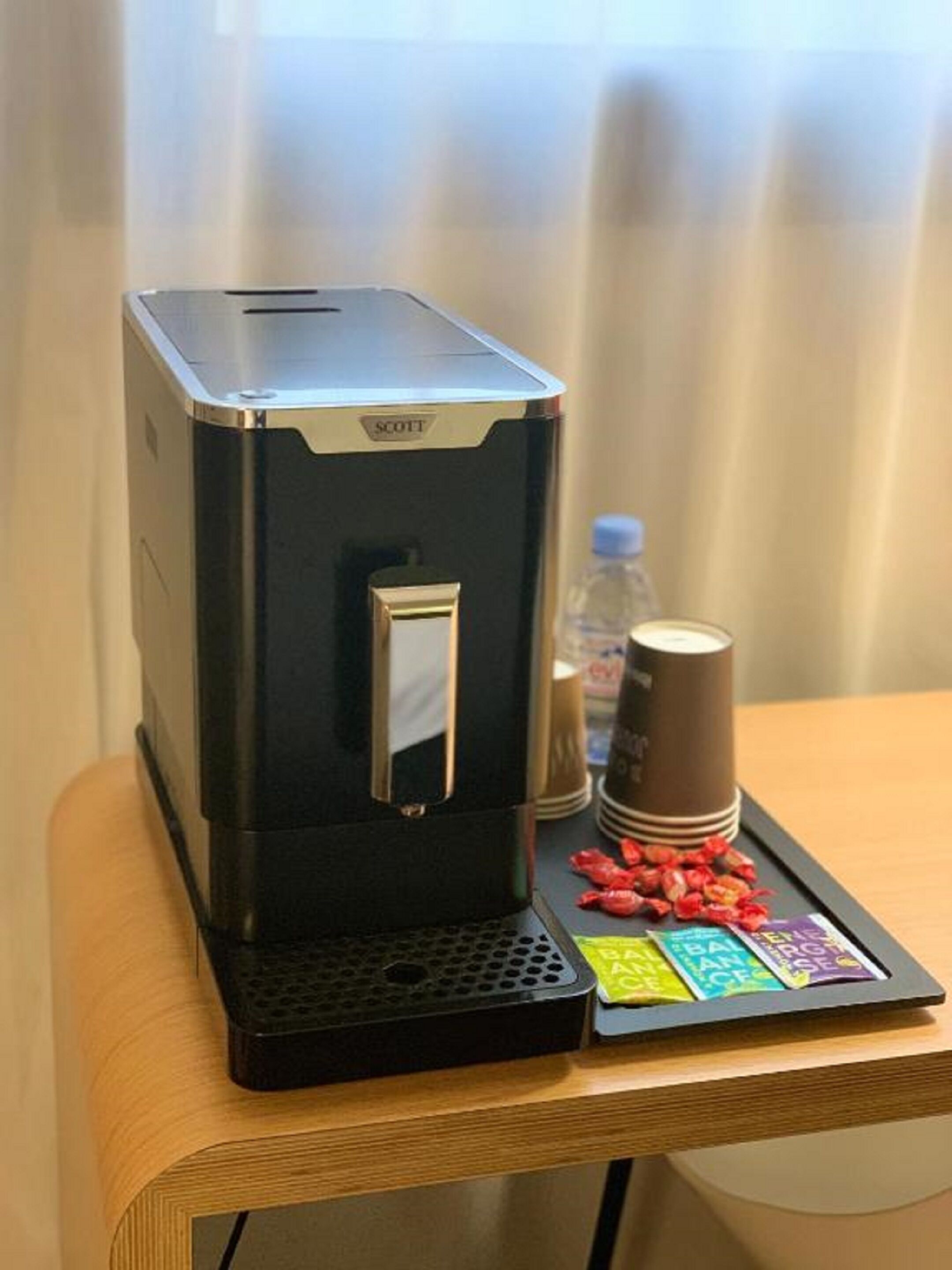 Une machine à café avec un plateau, posée sur une table en bois.