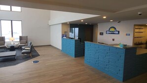 Vastaanottoalue, jossa on sininen palvelutiski, Days Inn -hotellin kyltti sekä oleskelualue, jossa on lamppu ja tuoleja.