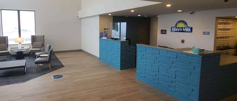 A reception area with a blue counter, a sign for Days Inn, and a seating area with a lamp and chairs.