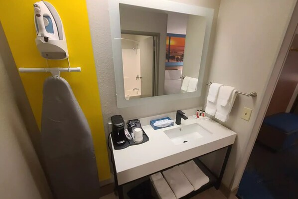 A hotel bathroom with a white sink, a mirror, a towel rack, and a hairdryer. - Days Inn by Wyndham Johnson Creek (Johnson Creek)