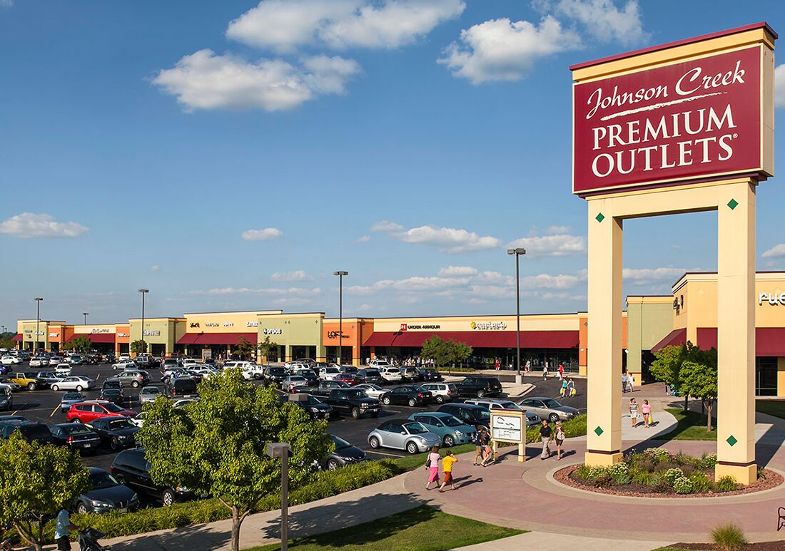 A shopping center with a prominent sign for Johnson Creek Premium Outlets.