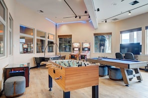 A room with a foosball table, pool table, and arcade games.