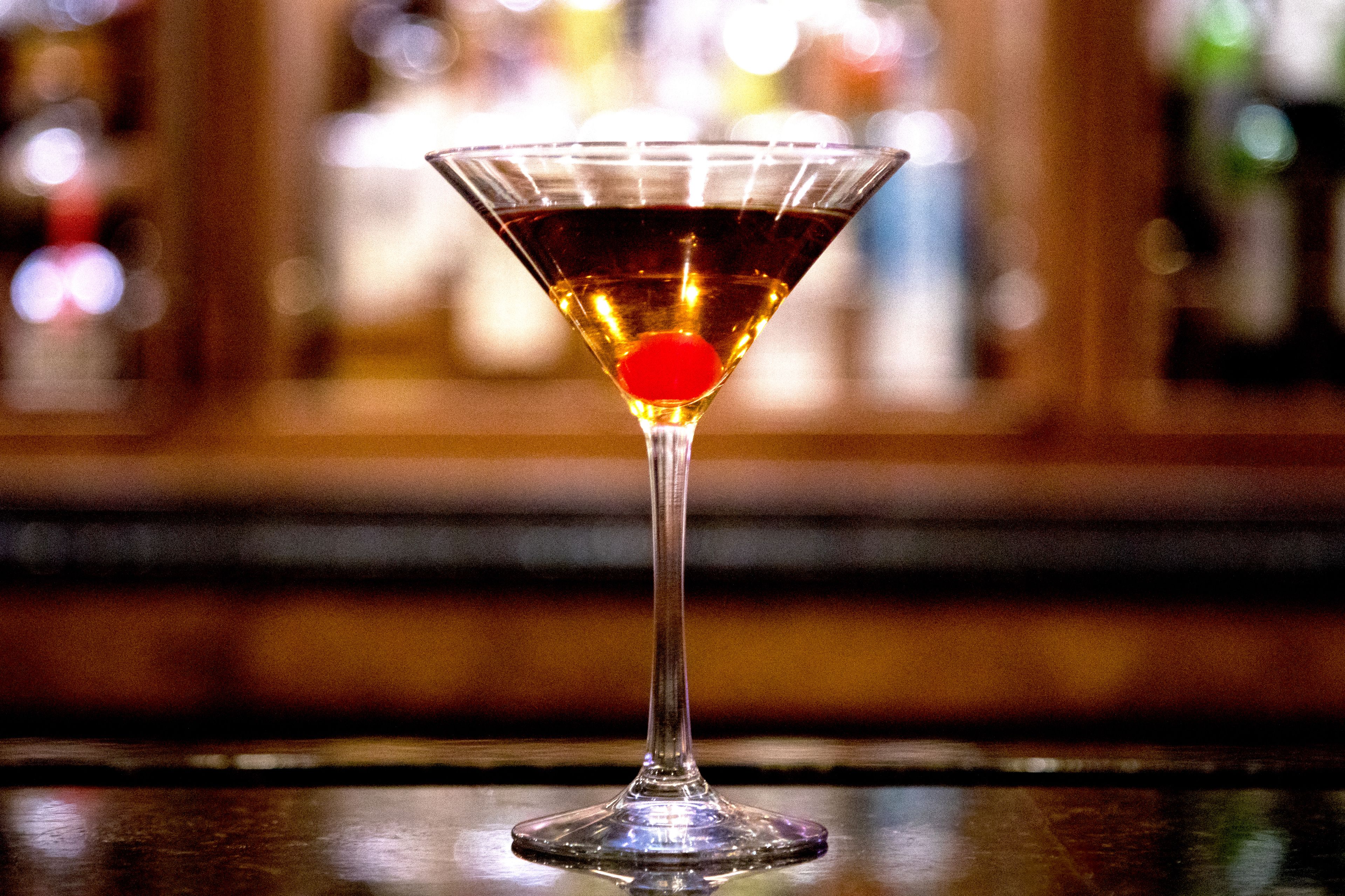 A martini glass with a red cherry on a bar counter.