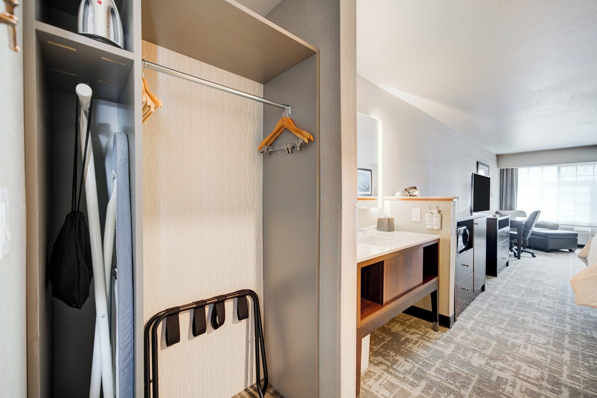 Une chambre d’hôtel comprenant un lit, un bureau, une chaise, une armoire et une salle de bain.