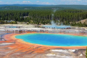 A large natural hot spring with a clear blue center surrounded by orange and red mineral deposits. - Holiday Inn West Yellowstone by IHG. (West Yellowstone)