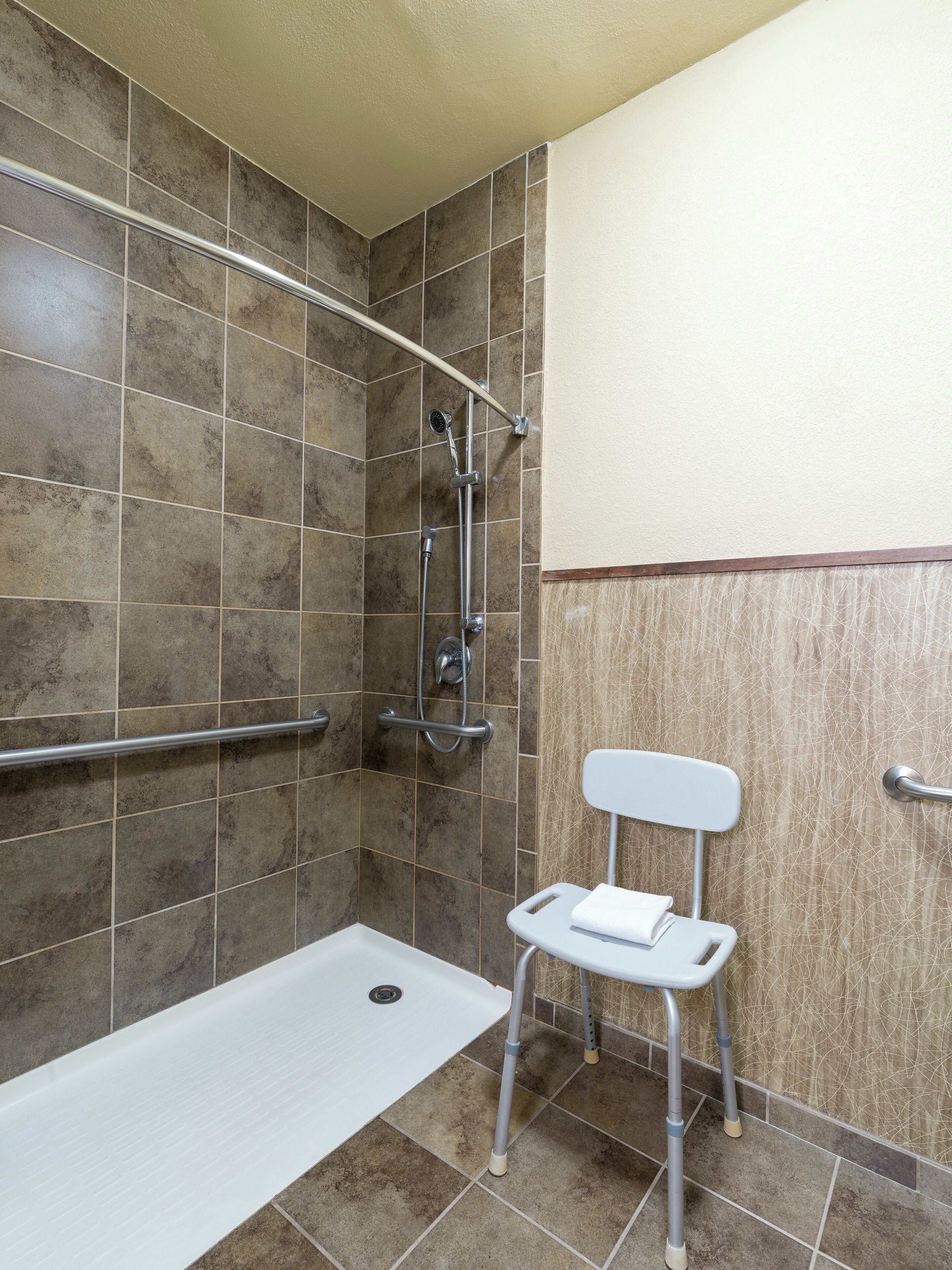 Un baño con ducha, inodoro y barra de apoyo.