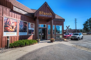 A restaurant named 'The Branch' with a rustic wooden exterior, large windows, and a visible entrance.