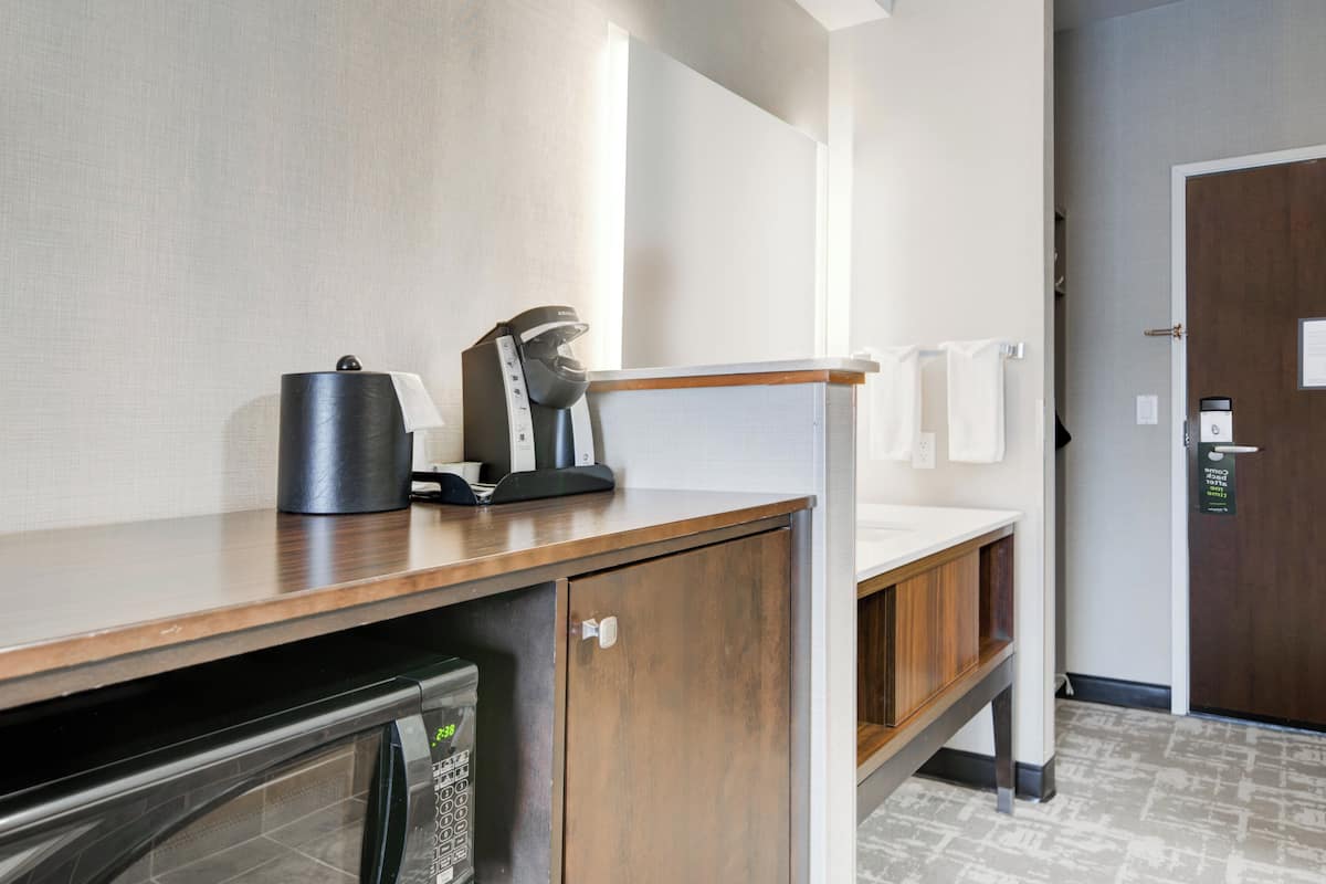 Baño de hotel con lavamanos, cafetera y microondas.