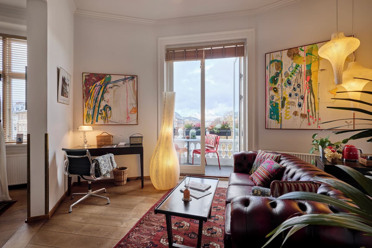 A living room with a sofa, a coffee table, a lamp, and a large window with a view of the outside.