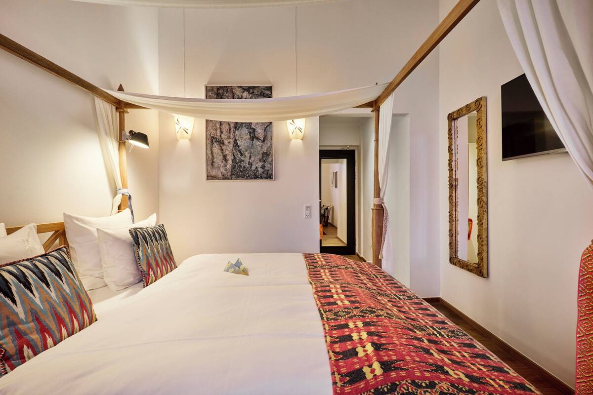 Habitación de hotel con una cama grande, un televisor de pantalla plana, un cuadro y un espejo en la pared.