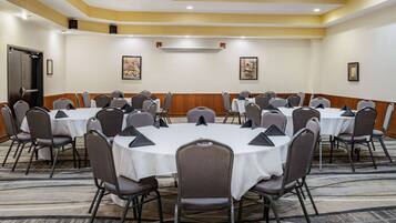 A conference room with round tables and chairs, a door, and framed artwork on the walls.