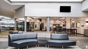 Un vestíbulo moderno con una zona de estar, mostrador de recepción y comedor.